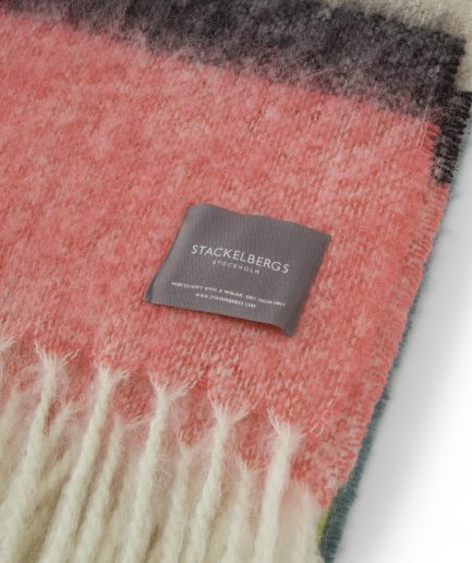 Close-up of the Stackelbergs logo on a luxurious stripe mint, yellow and pink Mohair plaid on a white backdrop.