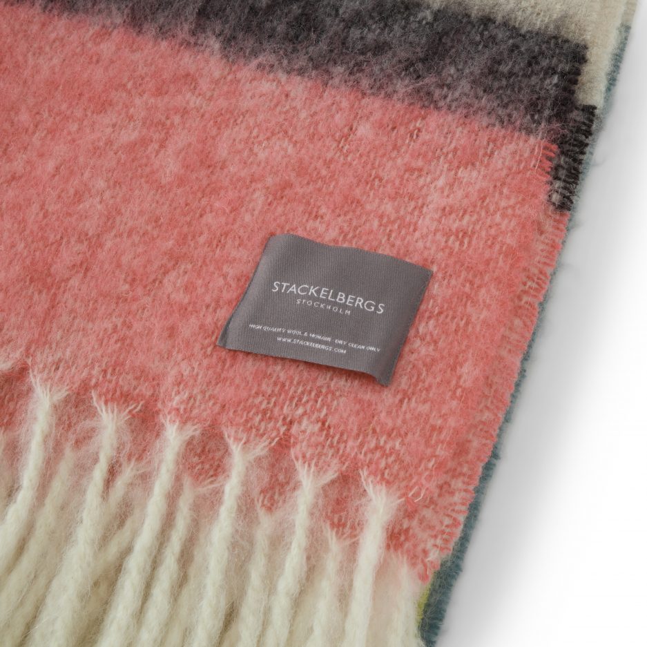 Close-up of the Stackelbergs logo on a luxurious stripe mint, yellow and pink Mohair plaid on a white backdrop.